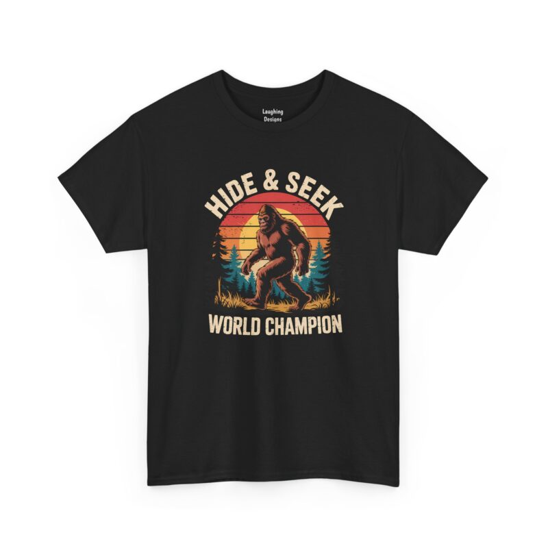 Bigfoot Hide and Seek World Champion T-Shirt - Retro sunset graphic featuring a detailed illustration of a walking Sasquatch in front of pine trees. Text reads "HIDE & SEEK WORLD CHAMPION" in distressed cream letters - Color Black.