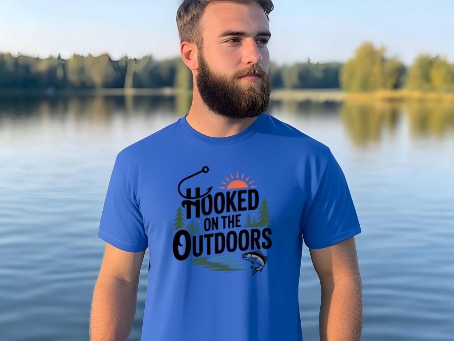 Funny Outdoors T-Shirts category image of a man wearing a blue shirt with a fishing design that says 'Hooked on the Outdoors' with a fish and hook graphic.