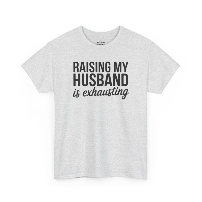 Funny wife t-shirt design featuring bold black text reading "RAISING MY HUSBAND" stacked above the words "is exhausting" in a cursive script font on a Ash Gray Tee.