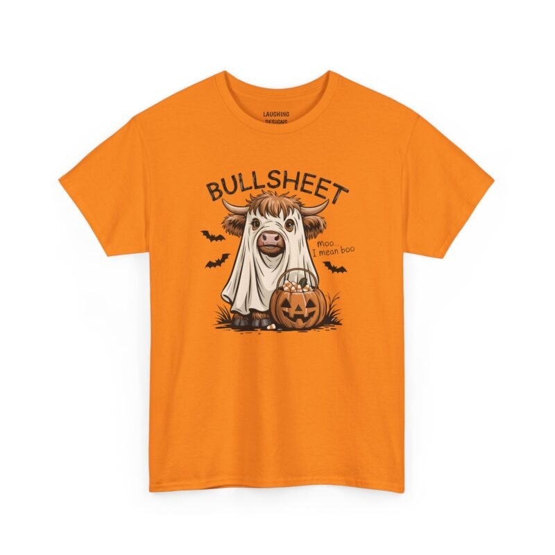 Funny t-shirt with a a highland cow wearing a white ghost sheet, standing next to a jack-o'-lantern bucket filled with candy corn, with black bats flying in the background. Arched text above reads "BULLSHEET" and text to the right reads "moo... I mean boo", printed on a Safety Orange color cotton shirt.