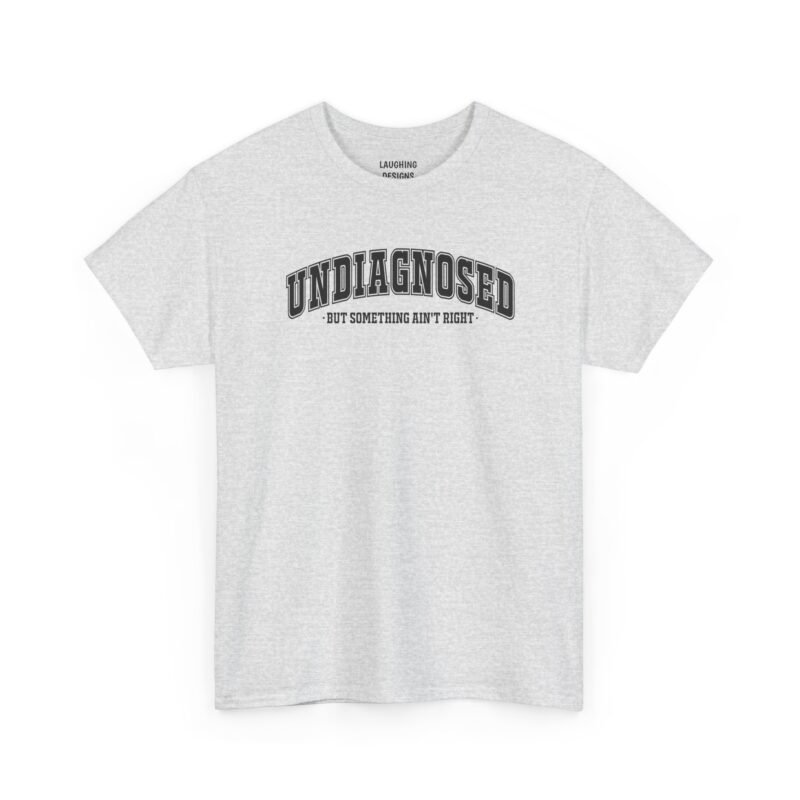 Funny t-shirt design with the text “Undiagnosed But Something Ain’t Right” in bold varsity-style black lettering, printed cleanly on a classic Ash Grey color cotton shirt.