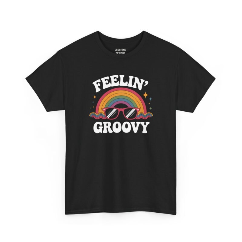 Retro 1970s style t-shirt design featuring a muted color rainbow with pink sunglasses, colorful waves, and starburst accents between the words "FEELIN' GROOVY" in white bubble letters, printed on a Black color cotton shirt.
