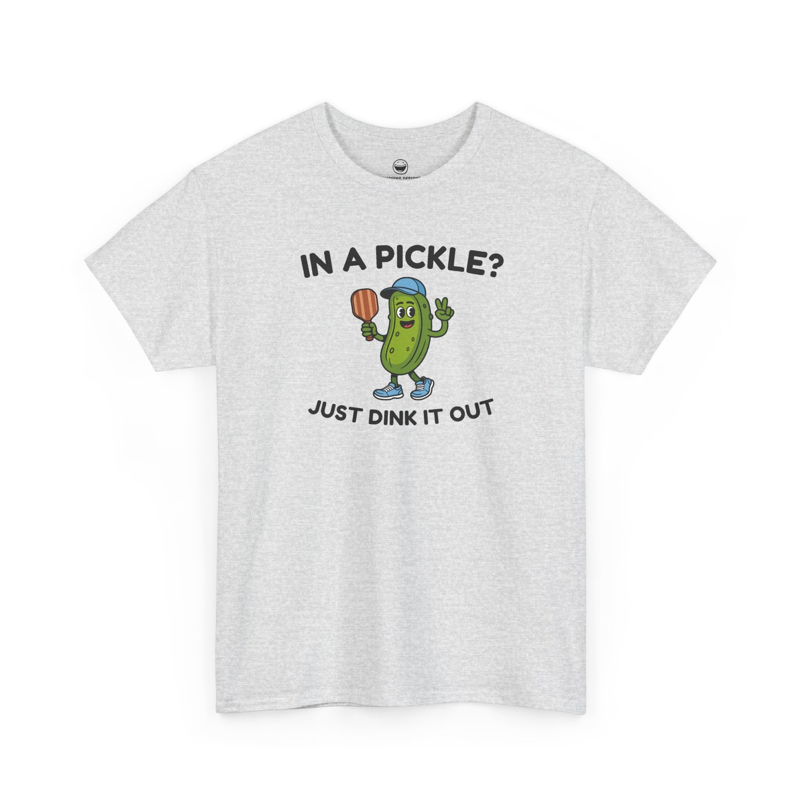 Funny Pickleball T-Shirt with a cartoon pickle character wearing a cap and holding a paddle between text reading "IN A PICKLE? JUST DINK IT OUT", printed on a Ash Gray color cotton shirt.