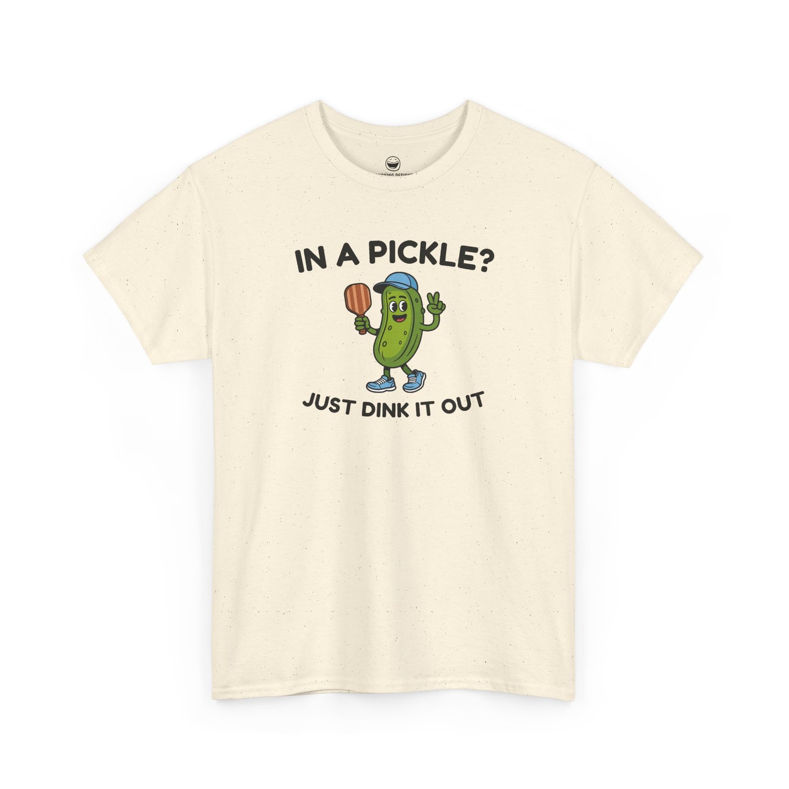 Funny Pickleball T-Shirt with a cartoon pickle character wearing a cap and holding a paddle between text reading "IN A PICKLE? JUST DINK IT OUT", printed on a Natural Cream color cotton shirt.