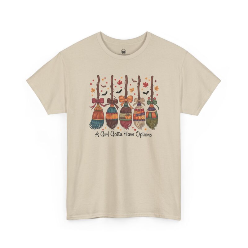 A Girl Gotta Have Options T-Shirt with five decorated witch brooms, autumn leaves, and quote A Girl Gotta Have Options on a Sand color cotton shirt.